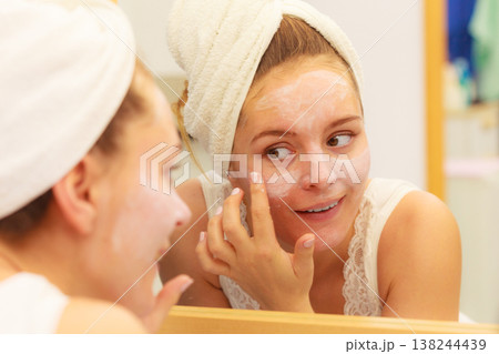 Woman applying mask cream on face in bathroom Woman applying mask cream on face in bathroom 138244439