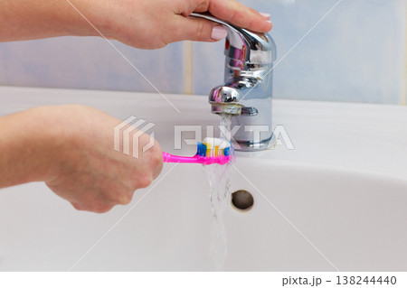 Hand holding toothbrush in bathroom Hand holding toothbrush in bathroom 138244440