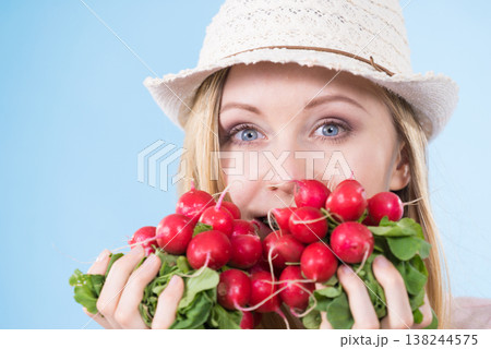 woman holding radish close to face 138244575
