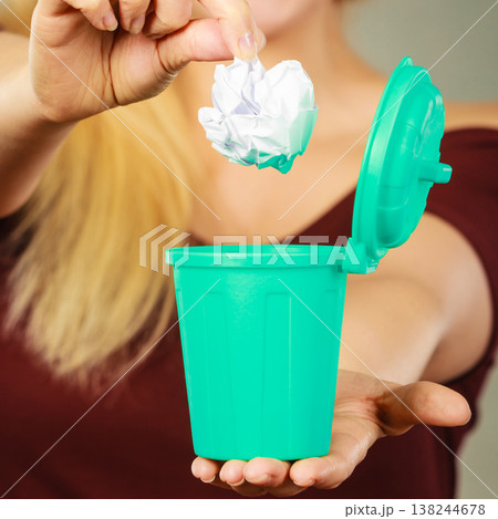 Woman putting paper into small trash can 138244678