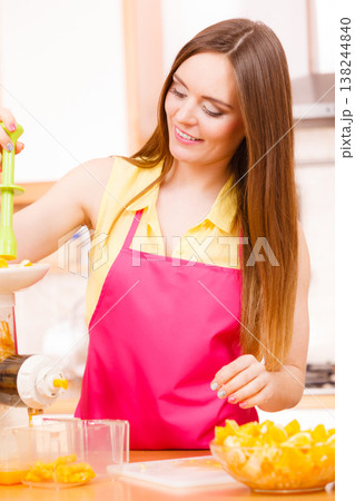 Woman making orange juice in juicer machine Woman making orange juice in juicer machine 138244840