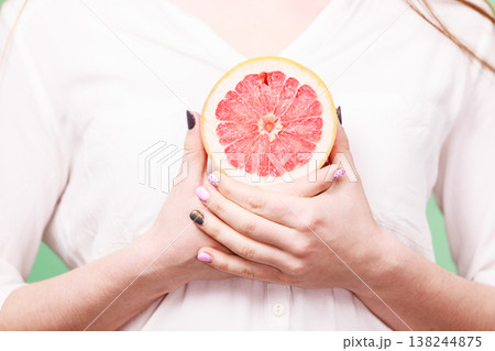 Woman holds half of grapefruit citrus fruit in hand 138244875
