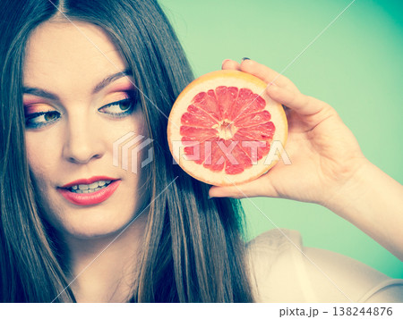 Woman holds half of grapefruit citrus fruit in hand 138244876