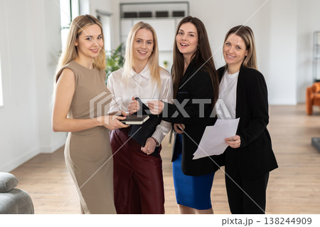 Four confident businesswomen stand together in a bright contemporary workspace. Smiling and collaborating. Showcasing teamwork. Leadership. And professional success in a thriving corporate environment 138244909