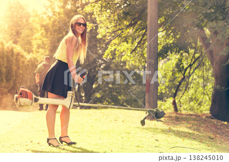 Girl with grass cutter in park. 138245010