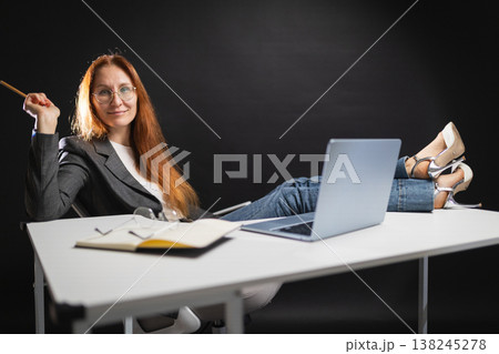 Confident businesswoman relaxing with feet on office desk Confident businesswoman relaxing with feet on office desk 138245278