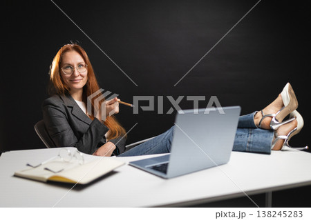 Confident businesswoman relaxing with feet on office desk Confident businesswoman relaxing with feet on office desk 138245283