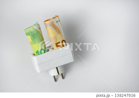 Euro banknotes in electric plug socket on white background. Concept of energy costs, rising electricity prices, inflation, utility bills and financial crisis in Europe 138247016