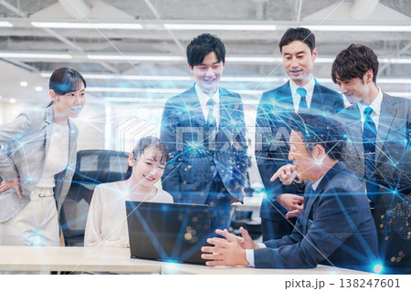 オフィスでパソコンを見ながらチームで話す人々 138247601