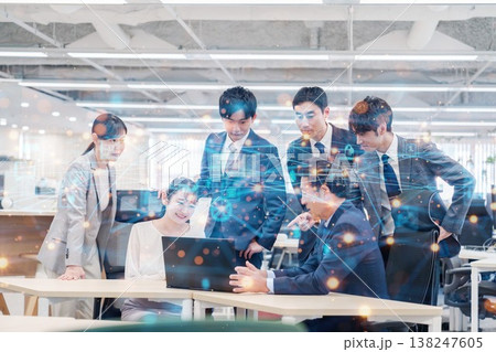 オフィスでパソコンを見ながらチームで話す人々 138247605