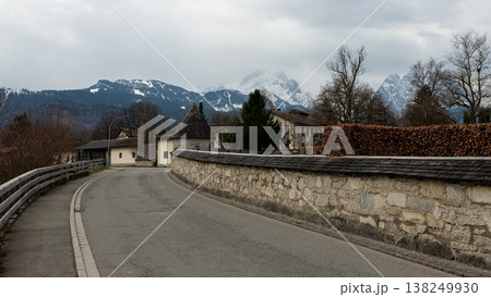 Curved village road with stone wall and snowy alpine mountains in Bavaria Curved village road with stone wall and snowy alpine mountains in Bavaria 138249930