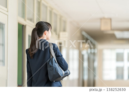 学校の廊下を歩く制服姿の小学生,中学生,高校生の女子生徒の後ろ姿 138252630