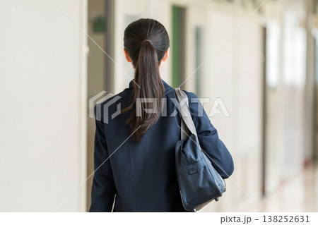 学校の廊下を歩く制服姿の小学生,中学生,高校生の女子生徒の後ろ姿 138252631