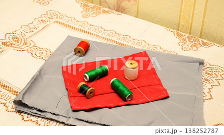 detailed view of spools of thread on patches of gray and red fabric on a lace table detailed view of spools of thread on patches of gray and red fabric on a lace table 138252787