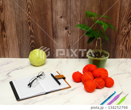 notebook and red yarn balls on a marble table 138252798
