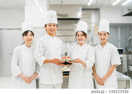 厨房・キッチンに立つコックコート姿の調理師・シェフ・コックの男女 138253592