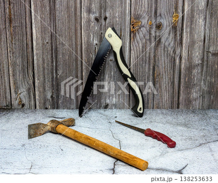 folding saw and carpenter hammer against wood wall 138253633