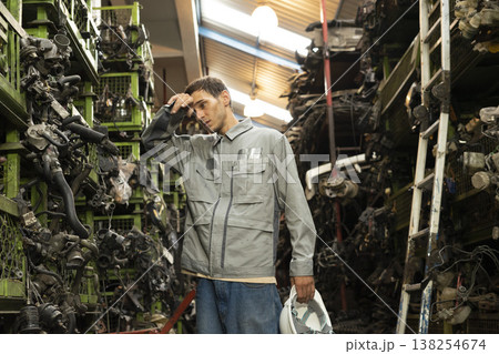 Technician worker feeling tired and frustration from working in garage scrap yard car workshop warehouse. Technician worker feeling tired and frustration from working in garage scrap yard car workshop warehouse. 138254674