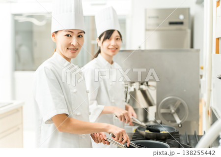 厨房でフライパンを使い調理するコック,シェフの女性スタッフ 138255442