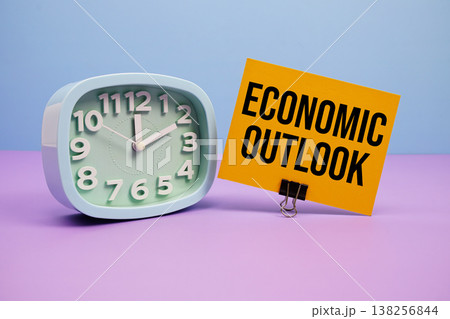 Economic Outlook text and alarm clock on blue and purple background Economic Outlook text and alarm clock on blue and purple background 138256844