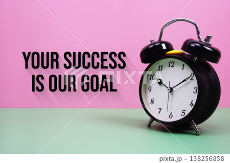 Black alarm clock on a pastel green and pink background with the text "Your Success Is Our Goal" Black alarm clock on a pastel green and pink background with the text "Your Success Is Our Goal" 138256858