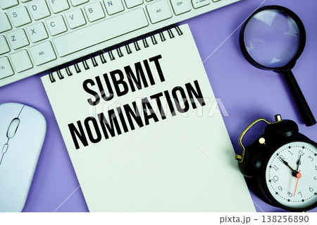 Notepad with the text "Submit Nomination" and white keyboard, wireless mouse, magnifying glass and alarm clock Notepad with the text "Submit Nomination" and white keyboard, wireless mouse, magnifying glass and alarm clock 138256890