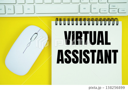 Notepad with the text "Virtual Assistant" with white keyboard and wireless mouse on yellow background 138256899