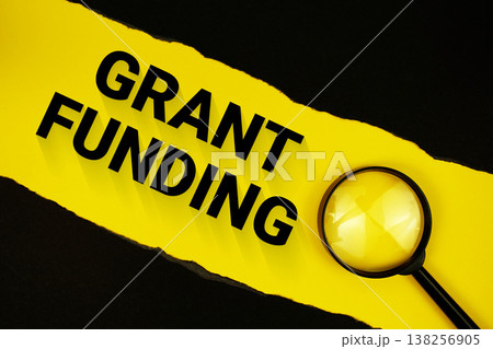 Grant Funding text on yellow with black paper torn ripped and magnifying glass Grant Funding text on yellow with black paper torn ripped and magnifying glass 138256905