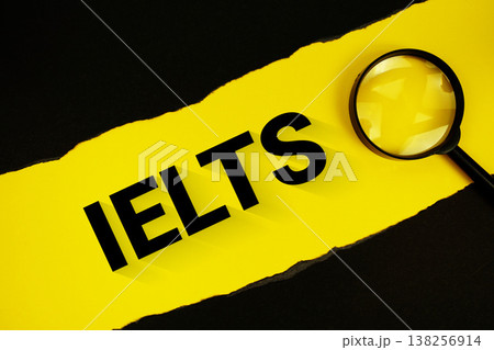IELTS text on yellow with black paper torn ripped and magnifying glass 138256914
