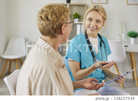 Conversation of smiling nurse and happy elderly patient in modern medical clinic Conversation of smiling nurse and happy elderly patient in modern medical clinic 138257339