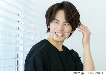 窓際に立って困った顔をする若い日本人男性のポートレート 窓際に立って困った顔をする若い日本人男性のポートレート 138259851