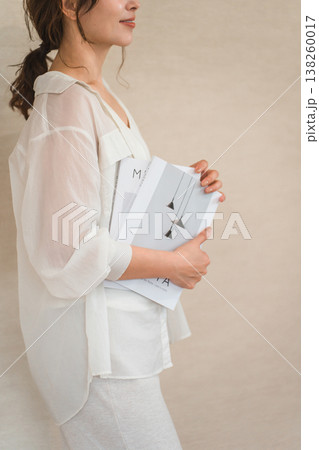 雑誌,本を持つお洒落な女性の手元 138260017