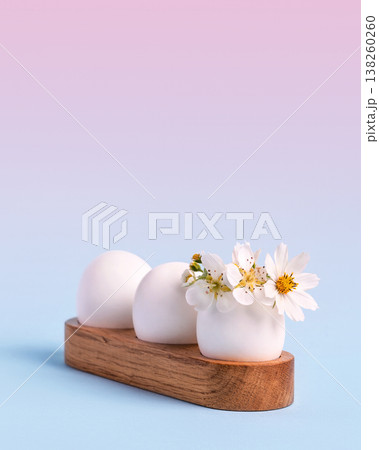 White Easter eggs in wooden stands with spring pear and strawberry flowers on a blue wooden table. Happy Easter 138260260