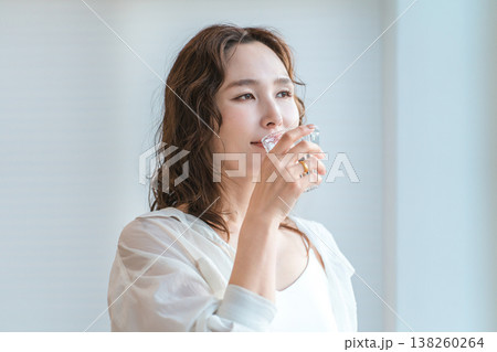 リビングでコップで水を飲み水分補給する女性 リビングでコップで水を飲み水分補給する女性 138260264