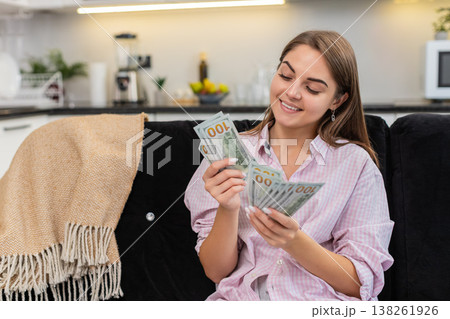 Young woman counts cash dollars smiles about salary savings plans big dream purchase and investments Young woman counts cash dollars smiles about salary savings plans big dream purchase and investments 138261926