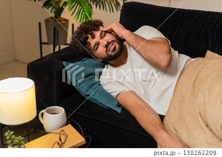 Arabian man lies with strong headache holds head at temple closes eyes feels pain needs rest tonight Arabian man lies with strong headache holds head at temple closes eyes feels pain needs rest tonight 138262209