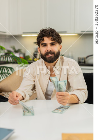 Indian man counting dollar cash saving in neat stacks planning budget dreaming about future purchase Indian man counting dollar cash saving in neat stacks planning budget dreaming about future purchase 138262270