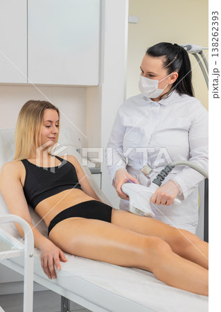 Woman receives cavitation vacuum massage on thighs in beauty clinic by professional cosmetologist Woman receives cavitation vacuum massage on thighs in beauty clinic by professional cosmetologist 138262393