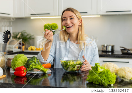 Young woman eating fresh vegetable salad for keto vegetarian meal in modern home kitchen lifestyle Young woman eating fresh vegetable salad for keto vegetarian meal in modern home kitchen lifestyle 138262417