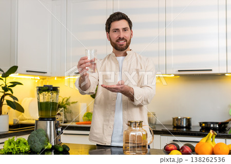Middle-aged man drinking water in kitchen for hydration wellness and healthy diet at home lifestyle 138262536