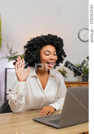 African American businesswoman gestures speaking into studio microphone recording podcast at laptop African American businesswoman gestures speaking into studio microphone recording podcast at laptop 138262543