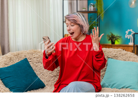 Young woman celebrating victory in online mobile game, expressing excited surprise joyful emotions Young woman celebrating victory in online mobile game, expressing excited surprise joyful emotions 138262658