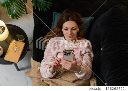 Adult woman lying down uses smartphone reads news before sleep top view relaxed mood dim night calm Adult woman lying down uses smartphone reads news before sleep top view relaxed mood dim night calm 138262722