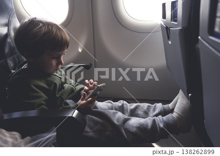 Child Using Smartphone on Airplane Seat During Flight 138262899
