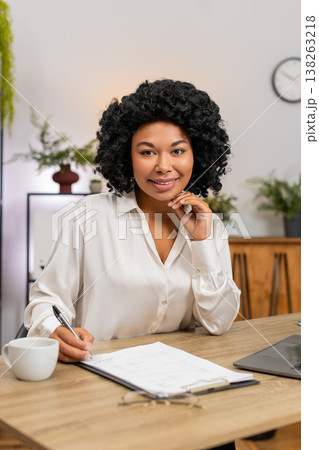 African American businesswoman signs important documents nods satisfied closing big successful deal African American businesswoman signs important documents nods satisfied closing big successful deal 138263218