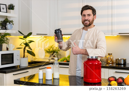 Middle-aged man mixing protein shake in kitchen smiling for fitness diet nutrition workout at home Middle-aged man mixing protein shake in kitchen smiling for fitness diet nutrition workout at home 138263269