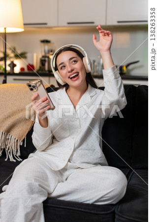 Young woman in wireless headphones enjoys music closes eyes smiles soft head sway calm mood evening Young woman in wireless headphones enjoys music closes eyes smiles soft head sway calm mood evening 138263358