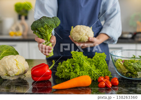 Woman holding broccoli and cauliflower selecting vegetables for healthy salad meal prep in kitchen Woman holding broccoli and cauliflower selecting vegetables for healthy salad meal prep in kitchen 138263360