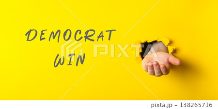 Hand emerging from yellow background, symbolizing victory, with the words "Democrat Win" displayed prominently, conveying a sense of achievement and celebration in a vibrant setting Hand emerging from yellow background, symbolizing victory, with the words "Democrat Win" displayed prominently, conveying a sense of achievement and celebration in a vibrant setting 138265716