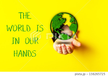 Hand holding a green globe symbolizing environmental protection and sustainability, with vibrant yellow background emphasizing the concept of ecology and our responsibility for the planet 138265725